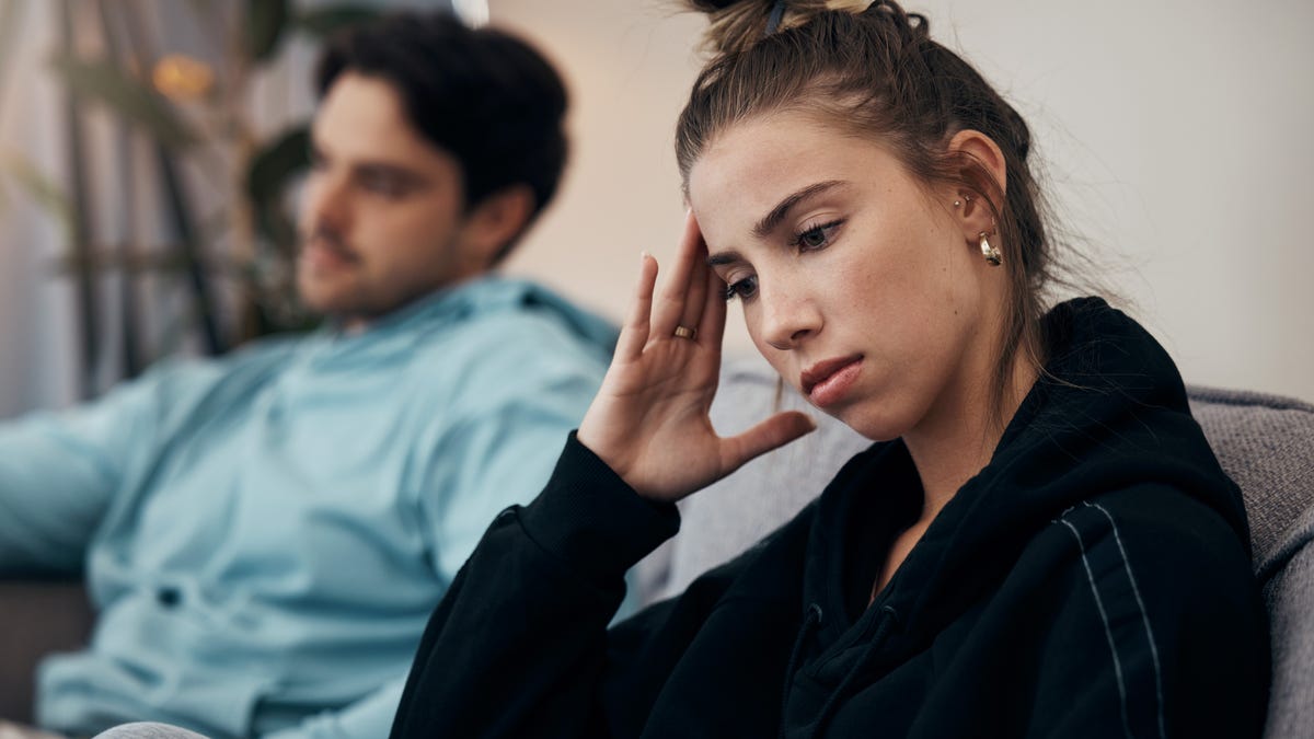 Frustrated couple, headache and fight on sofa in divorce, disagreement or conflict in living room at home. Man and woman in toxic relationship, cheating affair or dispute on lounge couch at house