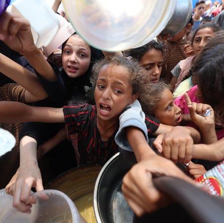 Palestinian children line up in Gaza to receive a hot meal at a food distribution point in Nuseirat on June 30, 2025.