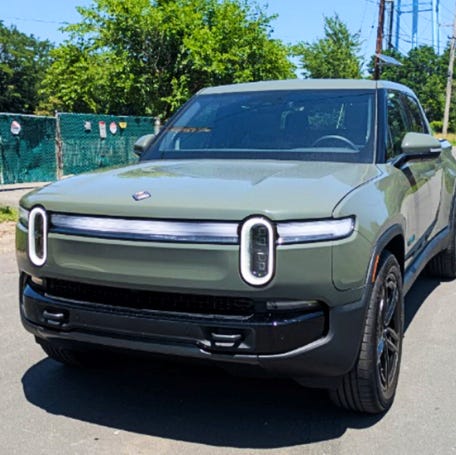 A Rivian R1T Quad electric pickup truck is parked.