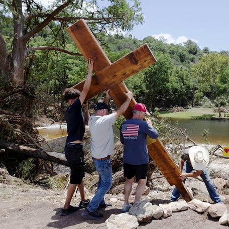 People place a cross by the Guadalupe River, across from Camp Mystic, following deadly flooding, in Hunt, Texas on July 10, 2025.