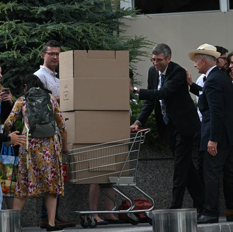 A fired State Department employee pushes his belongings in a shopping cart as he leaves the building in Washington, DC, on July 11, 2025.