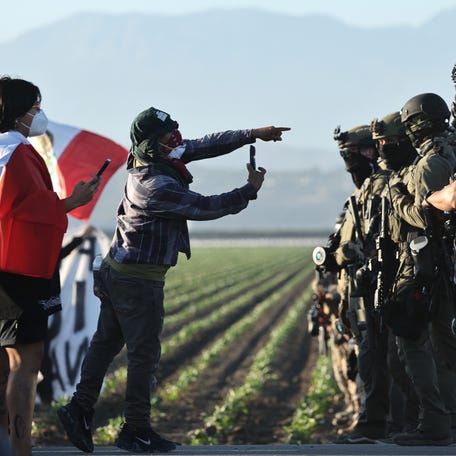 Federal agents block people protesting an ICE immigration raid at a nearby cannabis farm on July 10, 2025 near Camarillo, California. Protestors stood off with federal agents for hours outside the farm in the farmworker community in Ventura County. A Los Angeles federal judge is set to rule Friday on a temporary restraining order which would restrict area immigration enforcement operations.