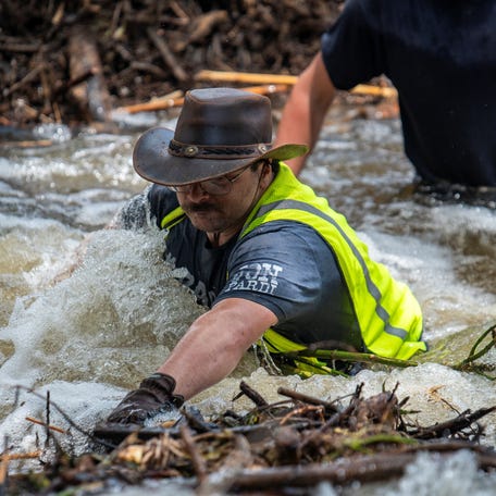 Brandon Myrtle stands in the Guadalupe River as he tries to clear debris after catastrophic floods in Center Point, Texas, U.S., July 11, 2025. REUTERS/Sergio Flores