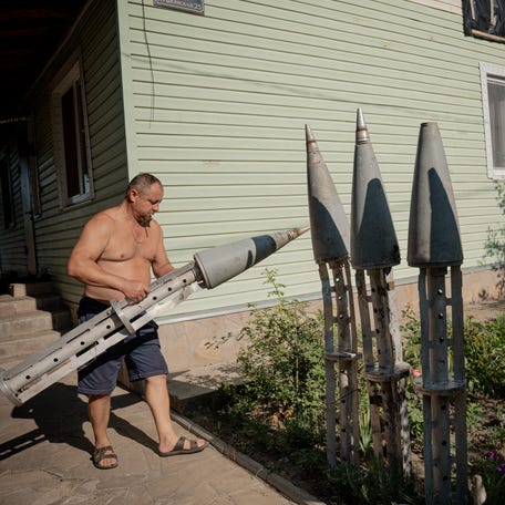 Ukrainian farmer Petro Pylypaka carries collected remains of a missile in the courtyard of his house in the de-occupied village of Ruski Tyshky, Kharkiv region on July 15, 2025, amid the Russian invasion of Ukraine.