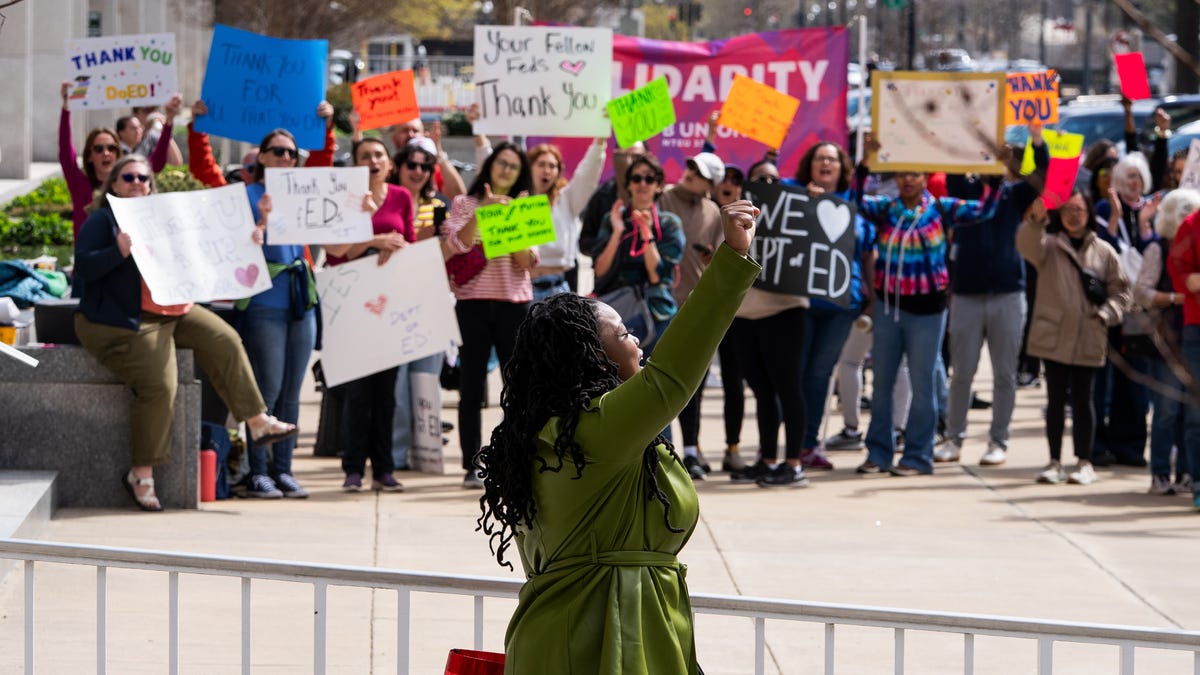 A U.S. Department of Education worker acknowledges a crowd of supporters after leaving the main agency building on March 28, 2025.