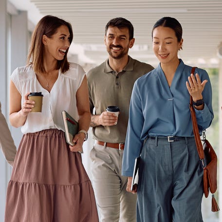 Business team walking in a hallway of an office building. Focus is on businesswomen talking.