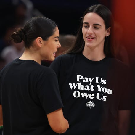 Team Clark guard Caitlin Clark (22) and Team Collier guard Kelsey Plum (10) wearing 'Pay Us What You Owe Us' shirts with the rest of the WNBA All-Stars to wArm up before the 2025 WNBA All Star Game at Gainbridge Fieldhouse.