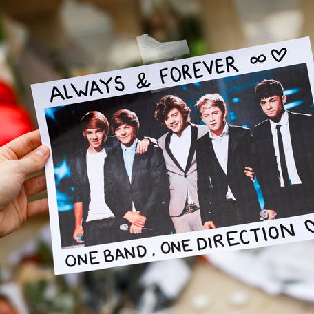 A person holds a poster with an image of One Direction band members as fans gather and place tributes to former One Direction singer Liam Payne, who was found dead after he fell from a third-floor hotel room balcony in Buenos Aires, in the Tuilleries Garden, Paris, France, October 20, 2024. REUTERS/Stephanie Lecocq