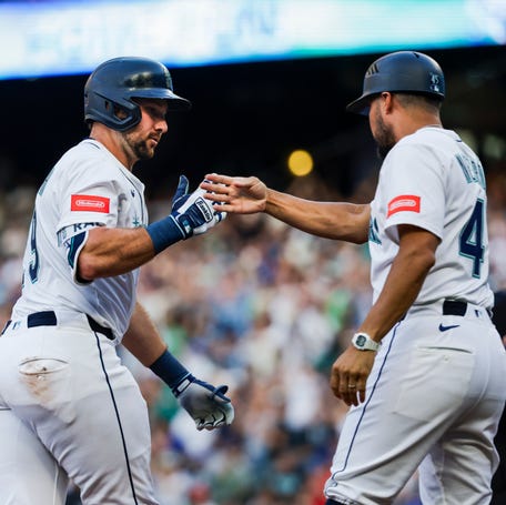The Seattle Mariners' Cal Raleigh (29) celebrates with third base coach Kristopher Negrón after hitting a solo-home run against the Milwaukee Brewers during the sixth inning at T-Mobile Park on July 22, 2025.