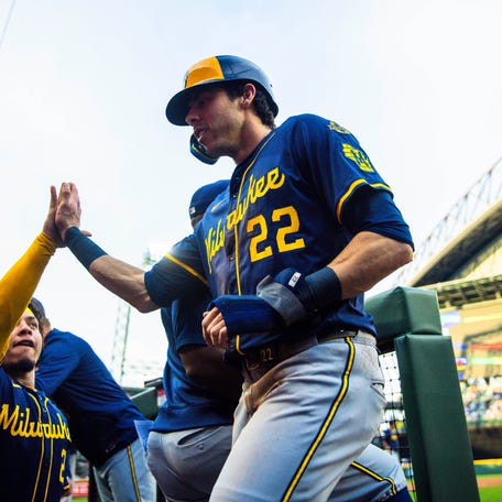 Christian Yelich celebrates with teammates in the dugout after scoring a run against the Seattle Mariners.
