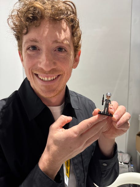 "Wicked" star Ethan Slater tries to match the smile of his Boq Woodsman Lego minifigure.