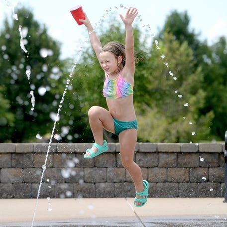 Juniper Wagahoff, 6, of Chatham cools down by running through the water jets at the splash pad in Southwind Park on July 23, 2025, in Springfield.