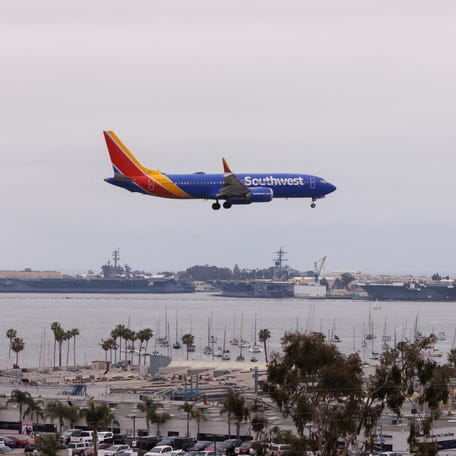 A Southwest commercial airline passes 2 U.S. Navy aircraft carriers at home port as it approaches to land in San Diego, California, on May 18, 2023.