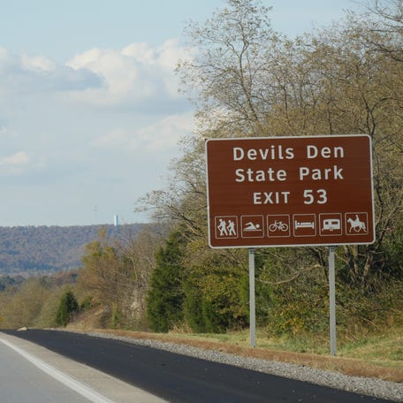 Roadside sign with exit directions to Devils Den State Park at Interstate 49, Arkansas.