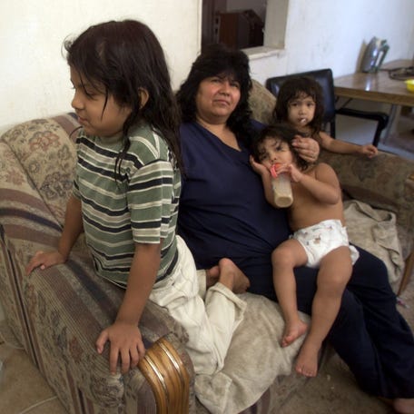 Maria Quesada has a hard time keeping her children comfortable in the hot summer heat. Daughter Crystal, 6, lets the fan blow on her as mom holds Yeceria, 2. Rosio Quesada, 3, is at right inside their Phoenix apartment in 2001.