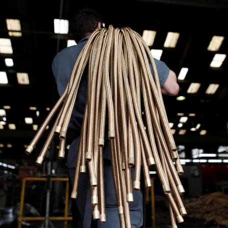 An employee carries copper hoses at the Sociedade Paulista de Tubos Flexiveis metallurgical company which manufactures flexible metal hoses, in Sao Paulo April 20, 2012.