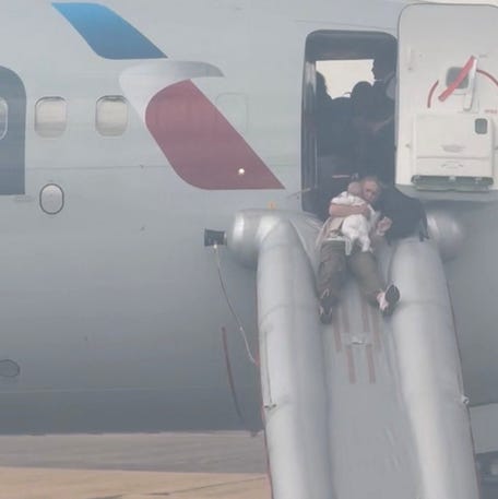 A passenger holding a baby evacuates an American Airlines plane by an emergency slide, at the Denver International Airport, Denver, Colorado, U.S. July 26, 2025, in this screengrab obtained from a social media video. @highlymigratoryfishing via Instagram/via REUTERS