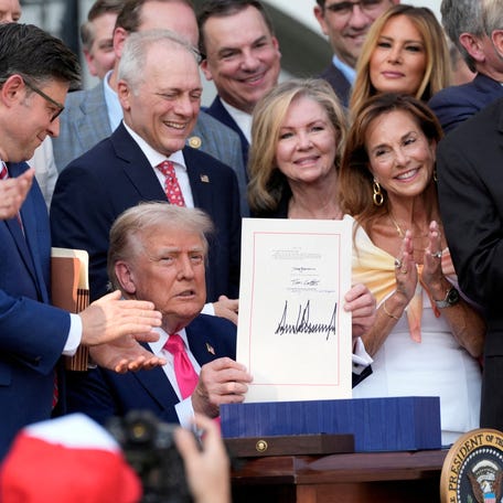 FILE PHOTO: U.S. President Donald Trump holds up his signed signature bill of tax breaks and spending cuts, ahead of the Fourth of July celebrations, at the White House in Washington, Friday, July 4, 2025. Alex Brandon/Pool via REUTERS  TPX IMAGES OF THE DAY/File Photo