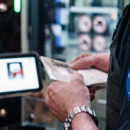 Police officers help passengers to go through a facial recognition verification system at the Terminal 2E of Roissy-Charles de Gaulle airport.