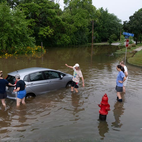 Neighbors gather to help Linda Bradshaw push her daughter's car out of the flood waters on the Menomonee River parkway.