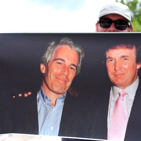 A protester holds up a photo of the future President Donald Trump with financier Jeffrey Epstein at a rally in Augusta, Georgia, on Aug. 2, 2025. Epstein, a convicted sex offender, died in a New York jail cell in 2019 while awaiting a federal sex trafficking trial.