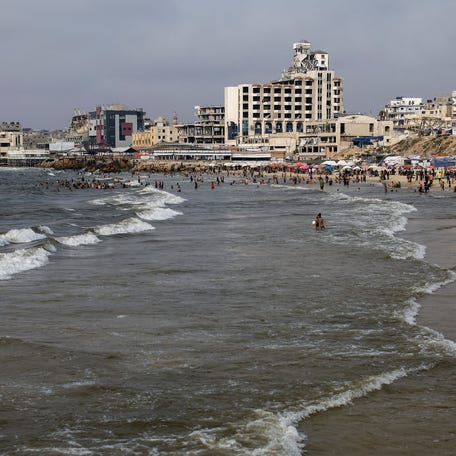 Palestinians, predominately displaced by the Israeli offensive, cool off in the seawater amid summer heat, in Gaza City, August 12, 2025.