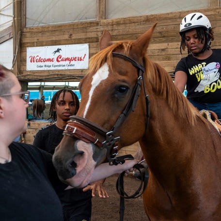 Morgan Bird, left, a riding instructor, and Jorden Blue, middle, a junior counselor, help a Detroit Achievement Academy student, Martionna Sutton, ride a horse during the Detroit Horse Power summer camp 2024 at the Cedar Ridge Equestrian Center in Ann Arbor on Tuesday, July 23, 2024.