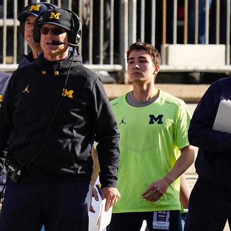 Michigan Wolverines head coach Jim Harbaugh watches from the sideline beside off-field analyst Connor Stalions.