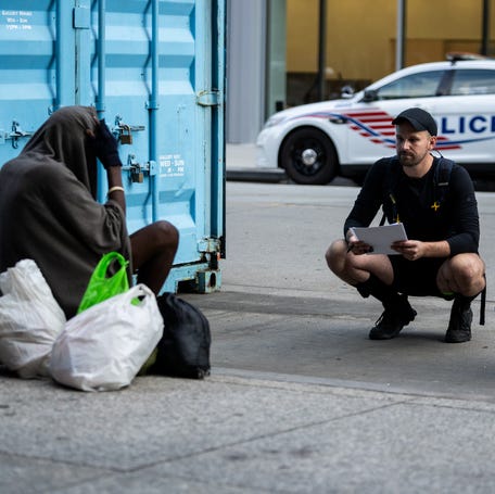 Two volunteers speak with a homeless man in Washington, DC, on Aug. 14, 2025.