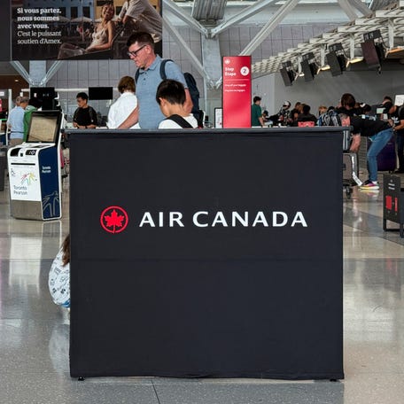 Passengers are pictured walking past an Air Canada sign at Toronto Pearson International Airport in Mississauga, Ontario, Canada.