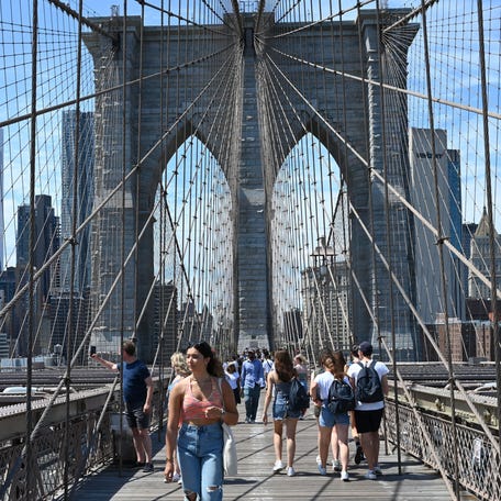 Downtown New York city skyline is seen as tourists cross the Brooklyn Bridge on July 31, 2022.