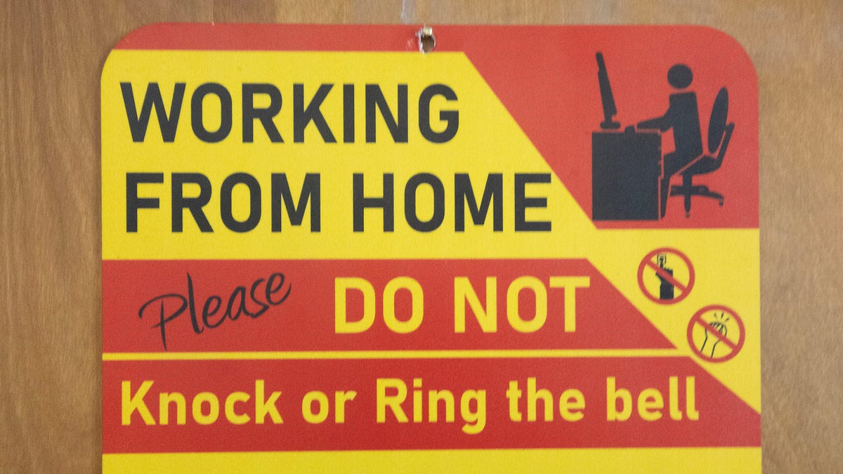 Shay Wilson hangs a warning sign on her North Canton, Ohio apartment doors as she works from home in March 2024.
