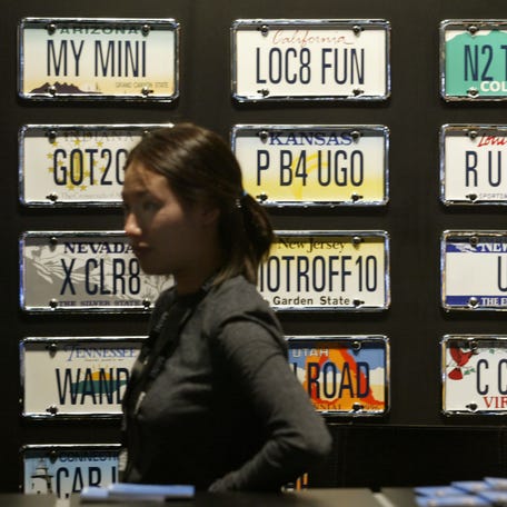 Mini Cooper representative Rhee Essig stands near a collection of vanity license plates, on display during a press preview of the Los Angeles Auto Show on Dec. 29, 2003.