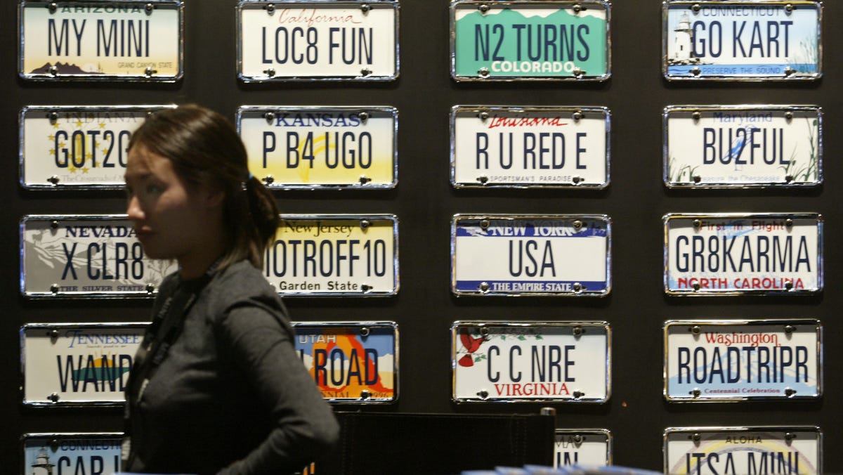 Mini Cooper representative Rhee Essig stands near a collection of vanity license plates, on display during a press preview of the Los Angeles Auto Show on Dec. 29, 2003.