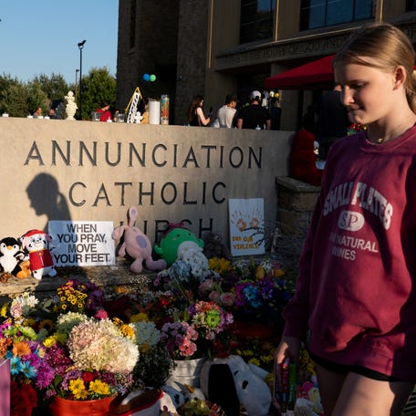A child walks past a memorial at the Church of the Annunciation, which is also home to an elementary school, to honor the victims of a recent shooting in Minneapolis, Minn., on Aug. 30, 2025.