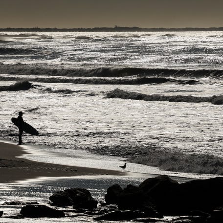 Surfers in silhouette take on the waves and wind from Hurricane Erin, the first hurricane of the 2025 Atlantic season, in the Atlantic Ocean at Lido Beach, New York, U.S., August 22, 2025. REUTERS/Shannon Stapleton