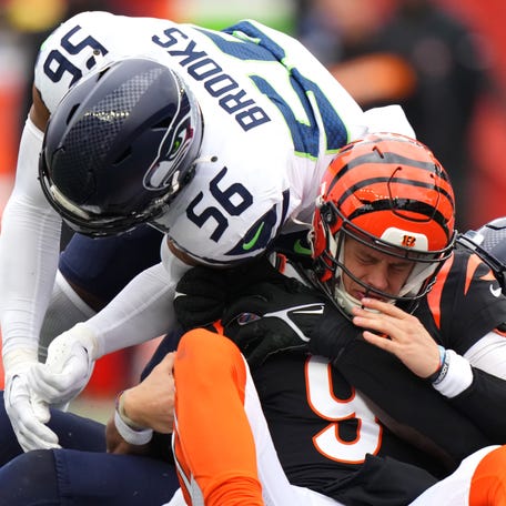Cincinnati Bengals quarterback Joe Burrow (9) is sacked by Seattle Seahawks defensive tackle Jarran Reed (90) and Seattle Seahawks linebacker Jordyn Brooks (56) in the third quarter during an NFL football game.