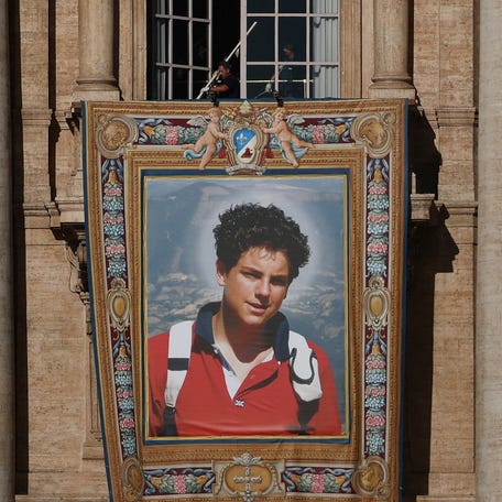 Workers install a tapestry on the facade of St. Peter's Basilica at the Vatican depicting an image of Carlo Acutis, a British-born Italian boy who will become the first millennial to be made a Catholic saint in a ceremony led by Pope Leo, as seen from Rome, Italy, September 4, 2025.