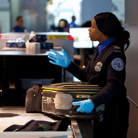A Transportation Security Administration security agent takes a traveler's luggage for a second security check at John F. Kennedy Airport in this file photo from Feb. 29, 2012.