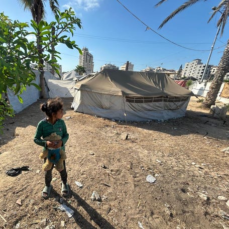 A child stands outside the tent where Farida Al-Ghoul, a writer and educator sheltering in northern Gaza, has been living with her younger siblings.