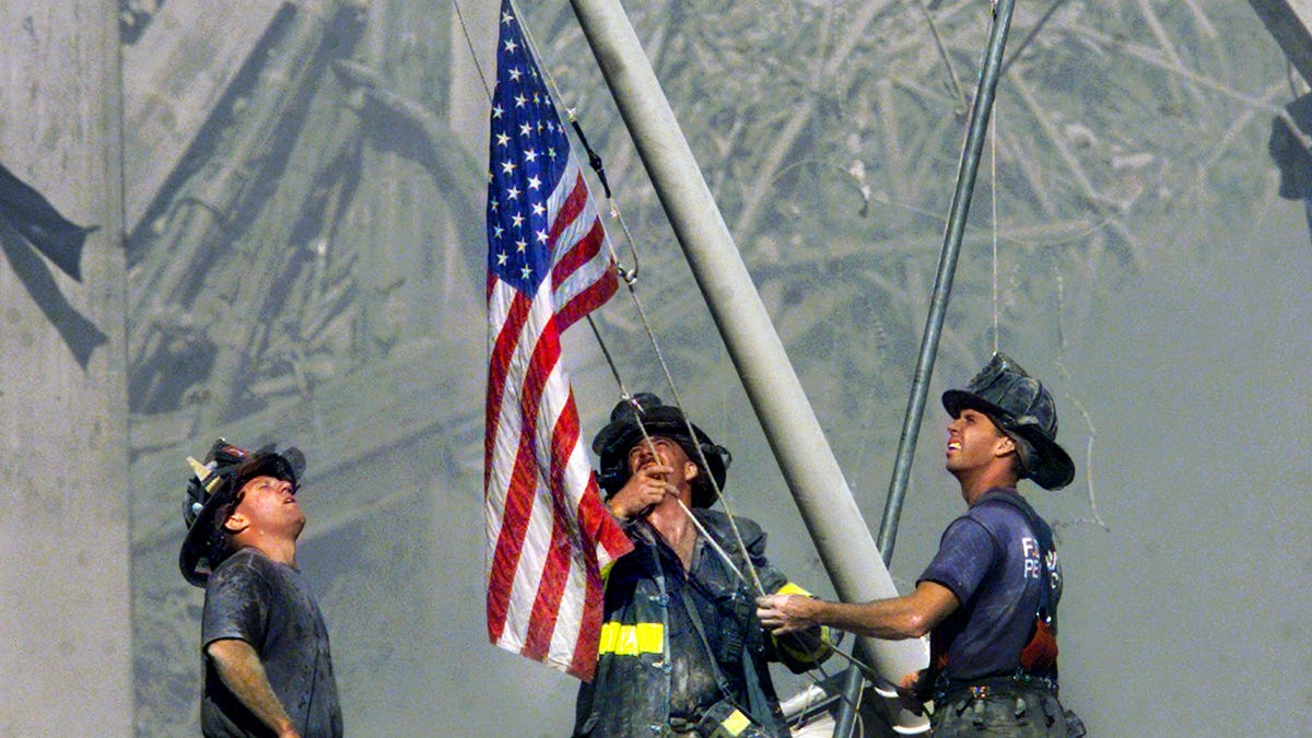 Three NYC firemen, George Johnson and Dan McWilliams and Bill Eisengrein, raise an American flag near the rubble of the World Trade Center. Taken at 5:01 p.m. on Sept. 11, 2001.