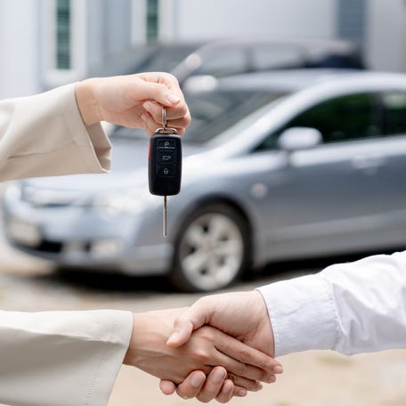 Dealership manager gives car keys to new owner.