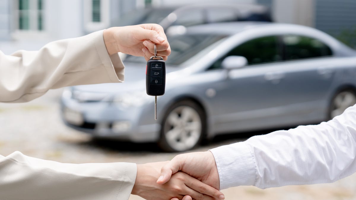 Dealership manager gives car keys to new owner.