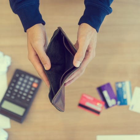 close up man hand opening empty wallet over calculator , debt expense bills monthly and credit card at the table in home office , managing payroll,money risk financial concept