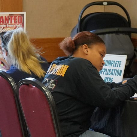 Job seekers fill out applications during a job fair.
