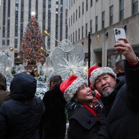 Two people snap a selfie in front of the Rockefeller Center Christmas Tree in Manhattan on Dec. 24, 2024.