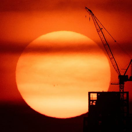 The sun sets behind a crane in Manhattan as an extreme heat warning is in effect in New York City, U.S., June 23, 2025.