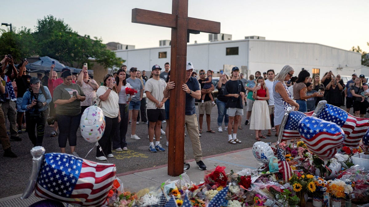 Dan Beazley, who drove to Phoenix from Michigan, holds a large wooden crucifix as people mourn following the fatal shooting of conservative activist Charlie Kirk, at the Turning Point USA headquarters in Phoenix, Arizona, on Sept. 12, 2025.