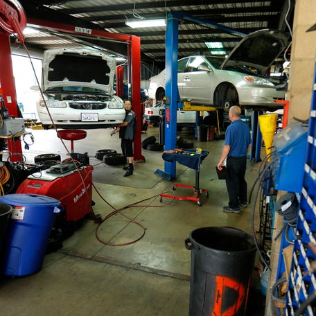 Mechanics work on cars at a garage in San Diego, California April 17, 2014.