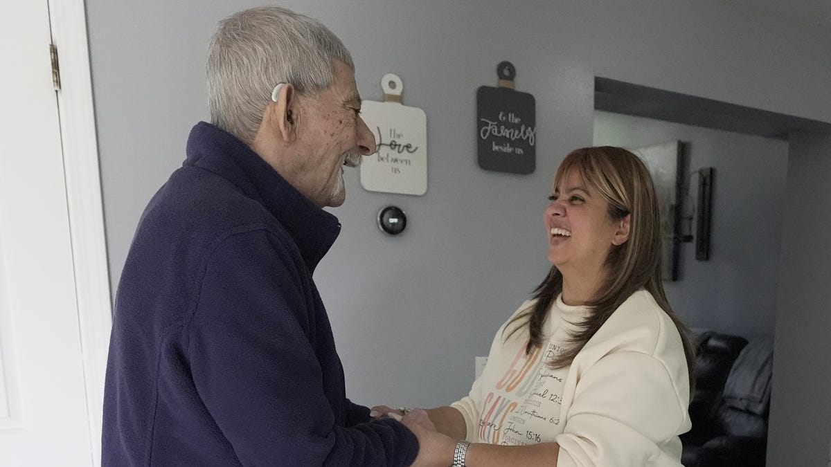 Jen Cortes laughs with her father Julio Rivera, who she is a family caregiver for, as they briefly dance to music before he gets tired and heads back to the living room sofa.